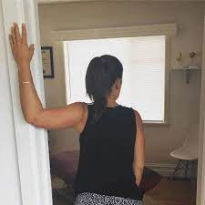 Woman using door frame to stretch arm